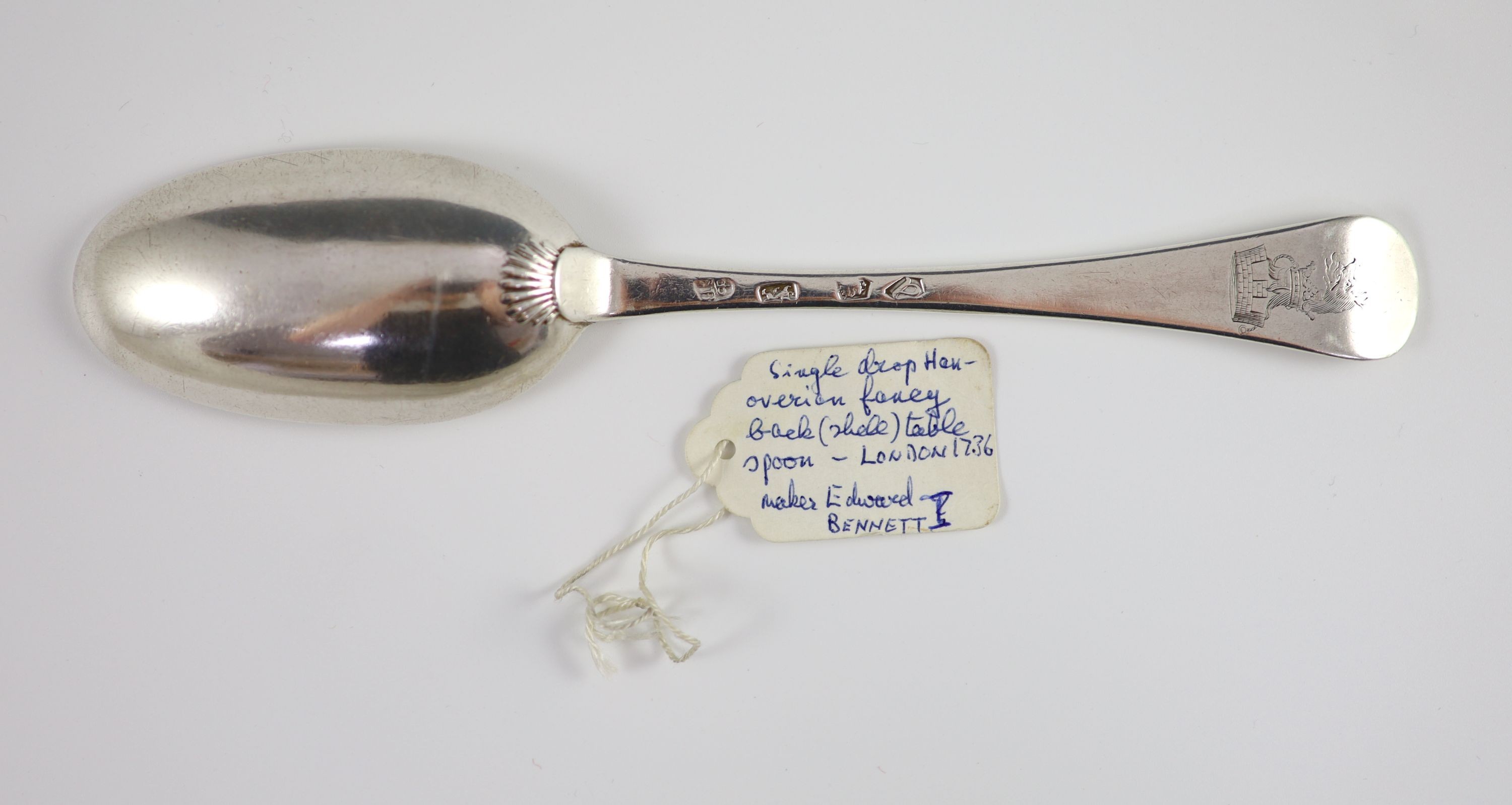 A George II silver Hanovarian pattern fancy back tablespoon, with engraved armorial, London 1736 by Edward Bennett, 20.5 cm long, 2.5 oz.